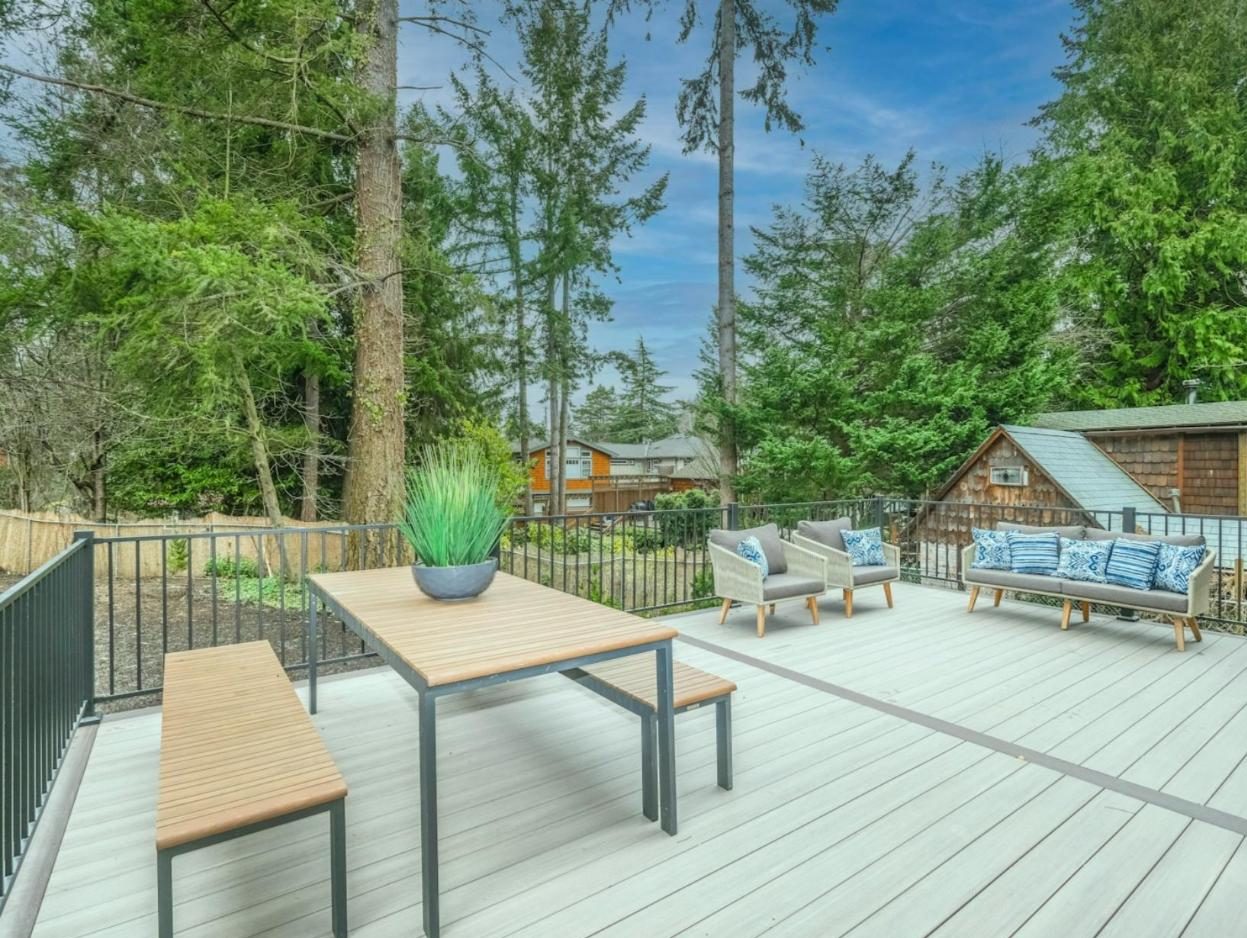 Light grey composite deck with black aluminum railing, dining table and lounge seating