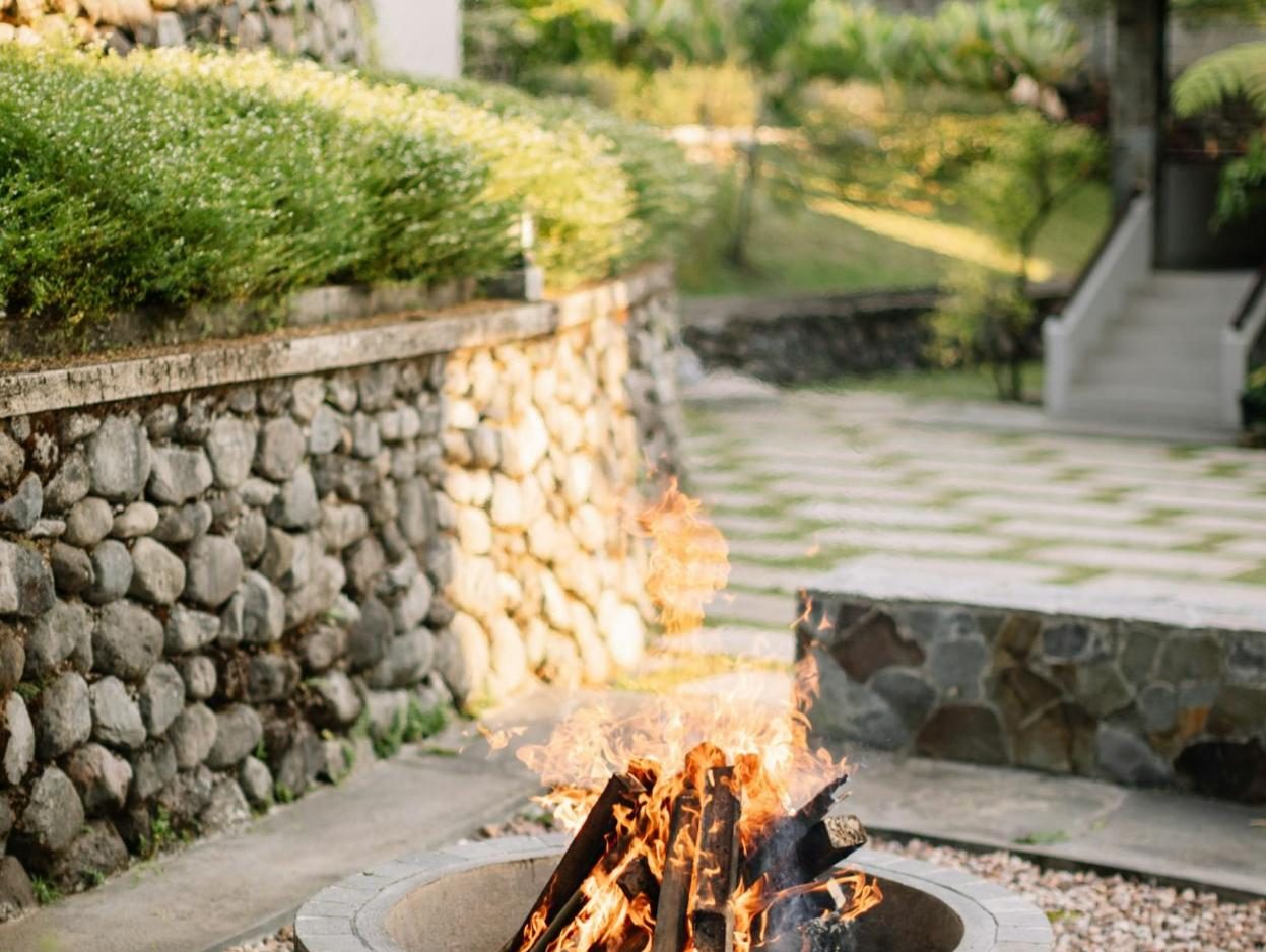 Wood fire in a fire pit beside a stone retaining wall