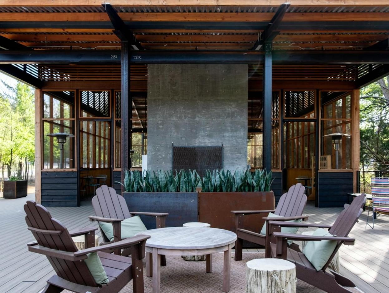 Covered outdoor room with a concrete fireplace and Adirondack chairs