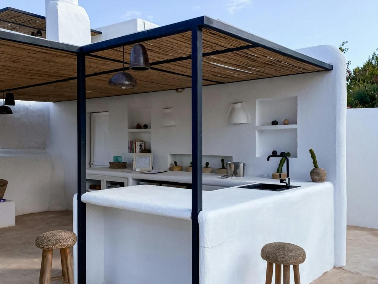 White plaster outdoor kitchen under a steel-framed shade roof