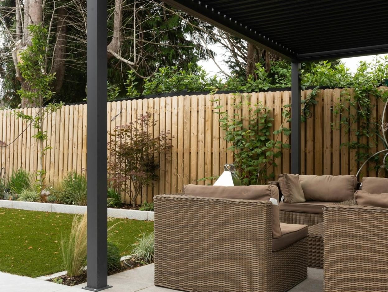 Patio with wicker seating under a black steel pergola